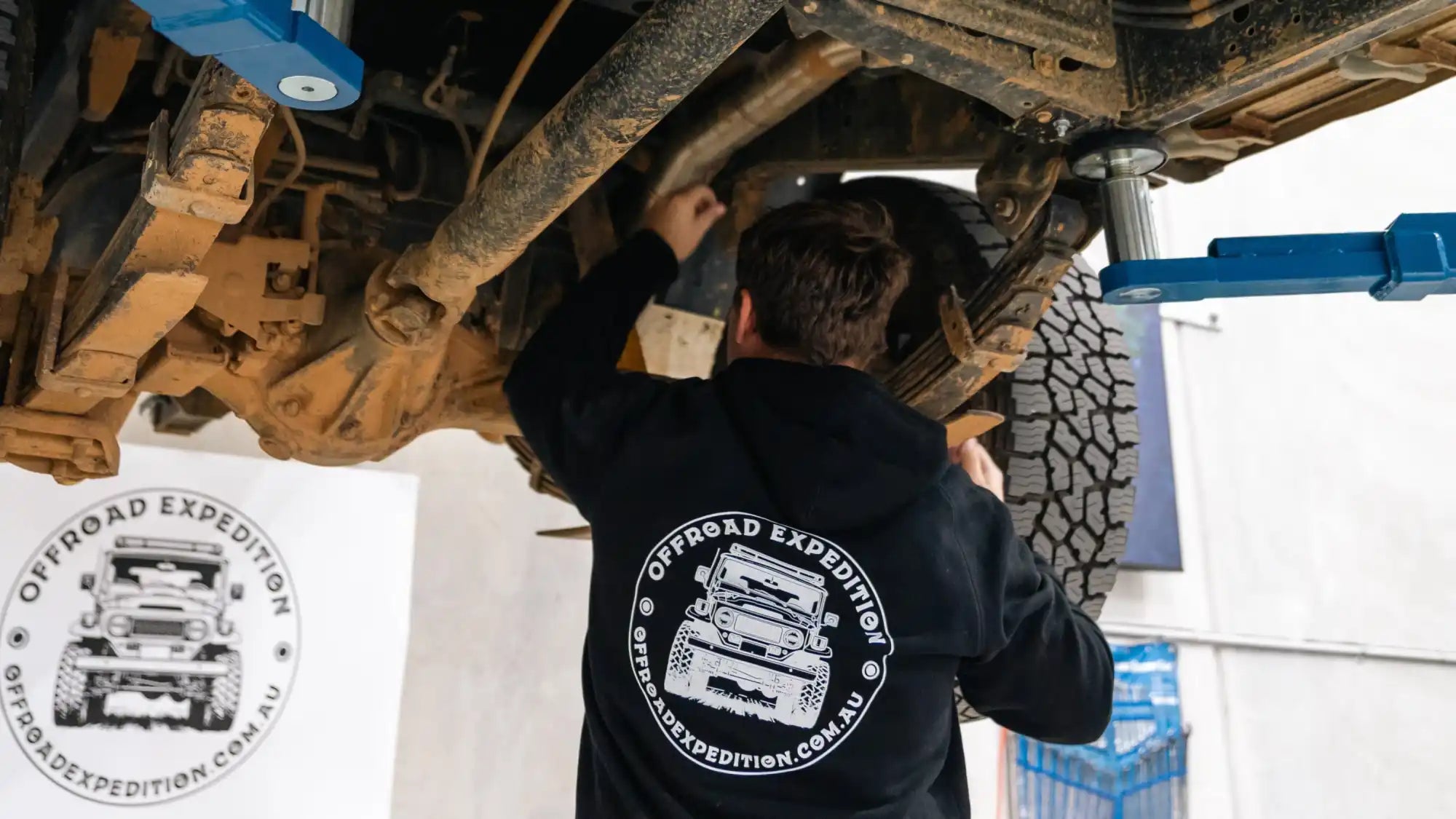 Mechanic working on the underside of an off-road vehicle.
