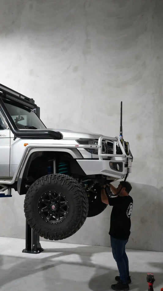 Silver off-road vehicle on a hydraulic lift.