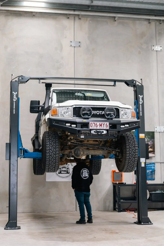 White Toyota Land Cruiser on a hydraulic lift.